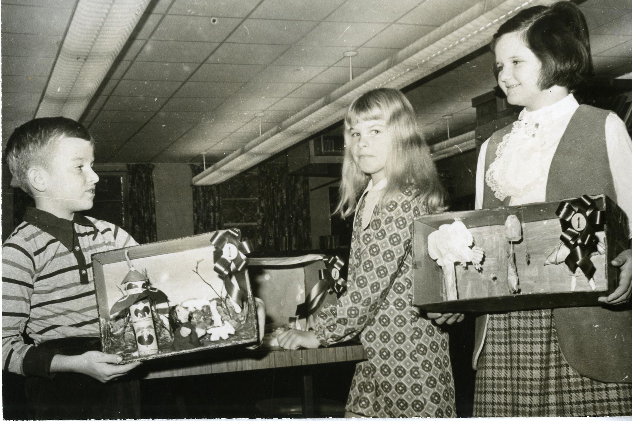 A photo by Ian Robertson of Belleville Public Library Young Canada Book Week Contest Walter McWilliams, age 8,left; Julie De Vries, age 7, centre; Caroline Julian, age 11, right holding awards for their displays.
